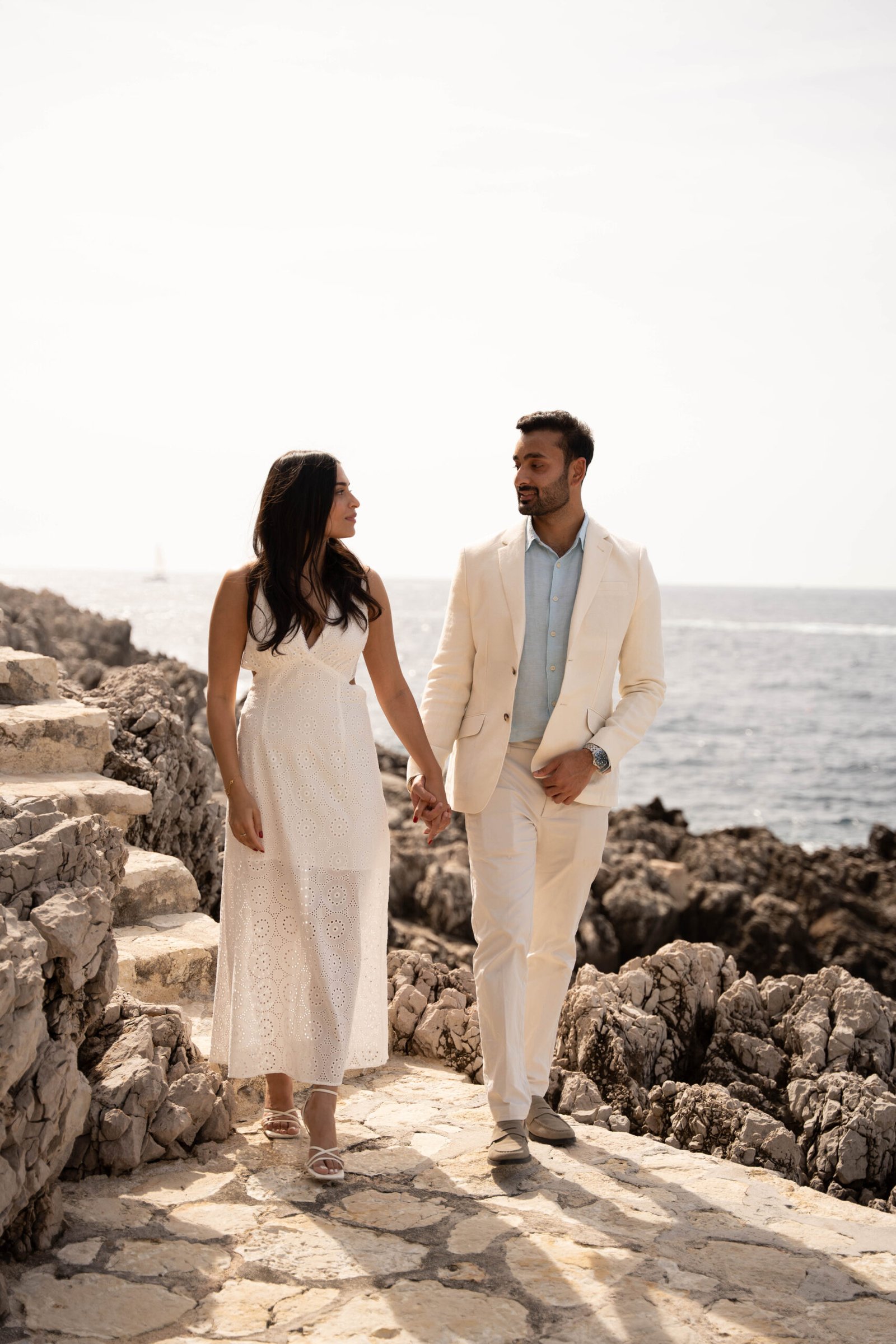 Romantic couple walking by the sea in St Jean Cap Ferrat on the French Riviera after a luxury marriage proposal.